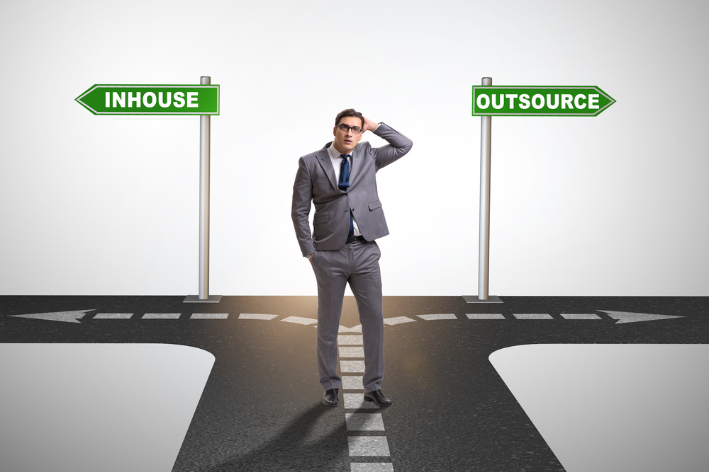 A man choosing between the outsourcing road or the in-house road