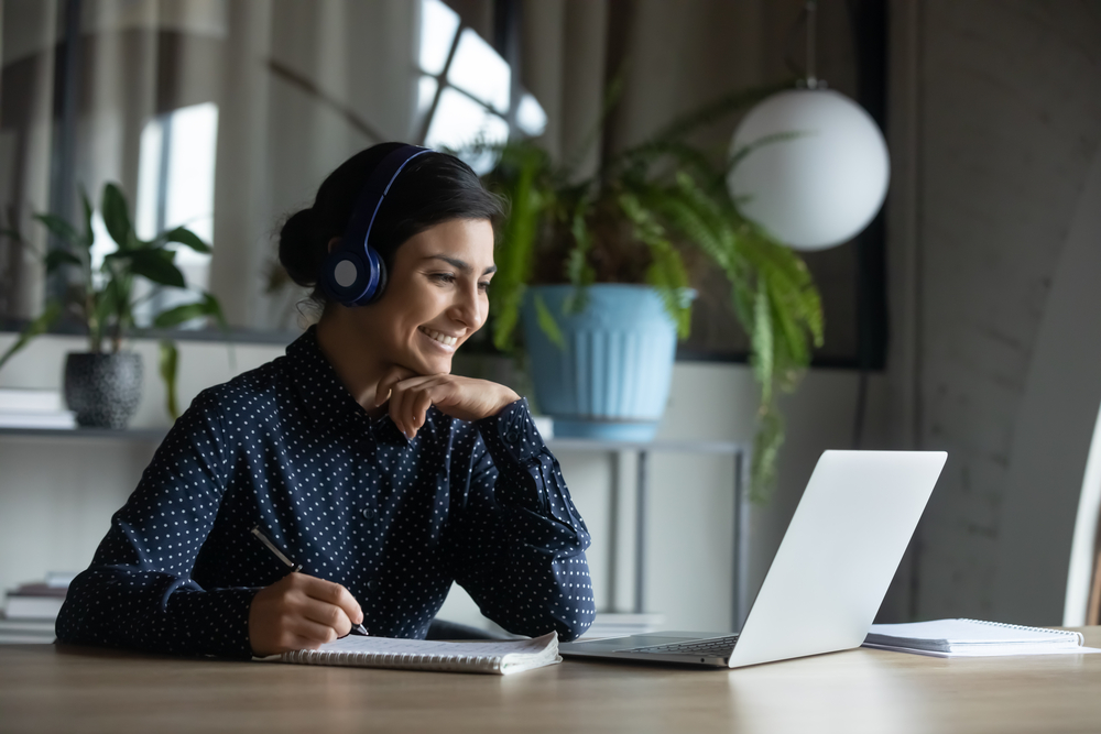 A woman working from home with her laptop and headphones